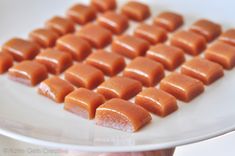 a person holding a plate with pieces of caramel candy on it and the other half is cut into cubes