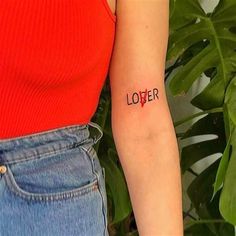 a woman's arm with the word lover tattooed on her left arm, in front of a plant