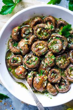 a white bowl filled with mushrooms covered in sauce