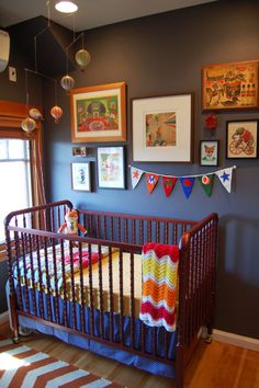 a baby crib in a room with pictures on the wall