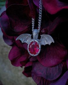 A realistic set of bat wings extruding from a deep red ruby centerstone. This sterling silver pendant utilizes a clawed prong setting to add to the aesthetic, as well as a traditional filigree design on its bail. A matching chain is included with purchase. Ruby Dragon, Bat Pendant, Red Lab, Filigree Design, Black Chain, Ruby Gemstone, Red Ruby, Bat Wings, Sterling Silver Pendant