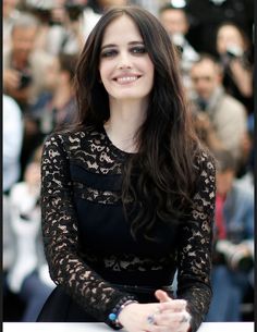 a woman with long dark hair smiles at the camera as she stands in front of photographers