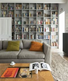 a living room filled with furniture and lots of bookshelves full of books on top of them