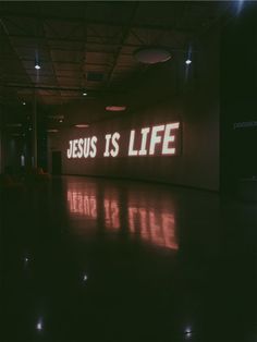 the words jesus is life are projected on a wall in an empty room with lights