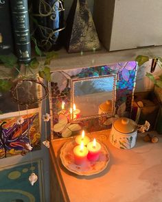 three lit candles sit on a plate in front of a mirror and bookshelf