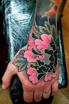 a person's hand with a flower tattoo on it