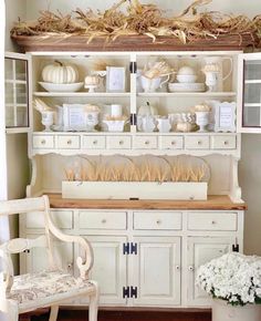 a white hutch filled with lots of dishes and vases on top of it