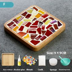 a wooden tray with different colored glass pieces on it and other items to make the mosaic tile