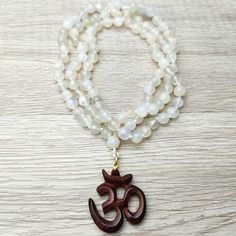 31" Unique Handcrafted Top Quality 7mm Moonstone Beads Knotted Necklace with Rosewood Om Carved Scared Symbol. Sacred Amulet, Gemstone, Meditation, Protection and Spiritual Healing Jewelry Gift. Handcrafted, Comes with A Velvet Pouch. ✥ Mala Necklace:31 Long - 7mm beads ❀❀❀ Please look closely at photos as part of item description, the product in the images is as the one you will receive and is sold "as is". Please review the description and images prior to purchasing to ensure this item meets y Knotted Necklace, Om Symbol, Moonstone Beads, Yoga Gifts, Hand Of Fatima, Mala Necklace, Healing Jewelry, Velvet Pouch, Knot Necklace