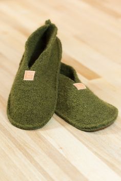 a pair of green slippers sitting on top of a wooden floor