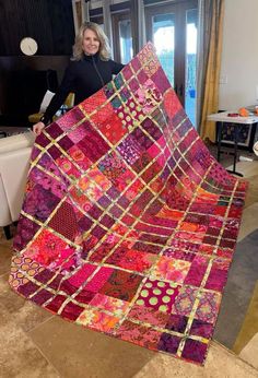 a woman standing next to a colorful quilt