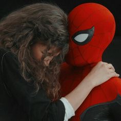 a woman with long hair hugging a spider man stuffed animal in front of her face