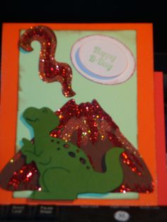 there is a card with a dinosaur on it and a happy birthday sign in the background