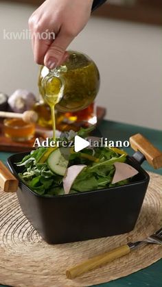 someone pouring olive oil over a salad in a pan