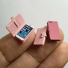 a small pink cell phone sitting next to an open wallet on someone's finger