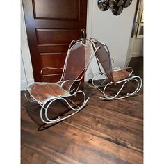 two metal rocking chairs sitting next to each other on top of a hard wood floor