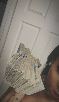 a woman is hiding behind a stack of money in front of a door with her shirt open