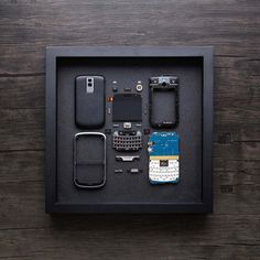 cell phone parts displayed in black shadow box on wooden table with dark wood flooring