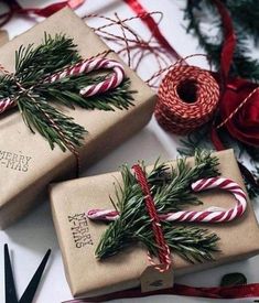 two wrapped presents sitting on top of a table next to christmas tree branches and twine