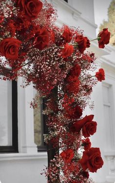 red roses and baby's breath are arranged on a pole in front of a white building