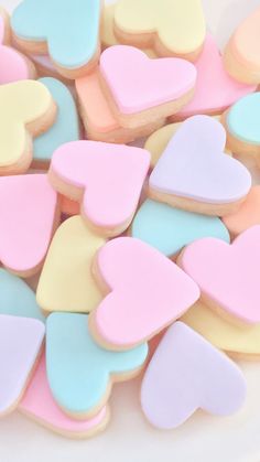 some heart shaped cookies are on a white plate with pink, blue and yellow frosting