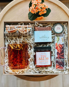 an open gift box containing honey, tea and candles