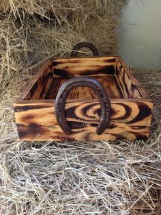 a wooden box with horse shoe handles on top of some hay and hay bales