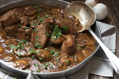 a pot filled with meat and mushrooms on top of a table