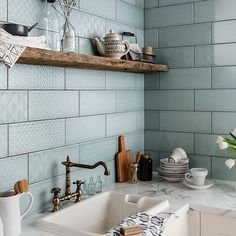 a kitchen with blue tiles and gold faucets on the counter top, next to a white sink