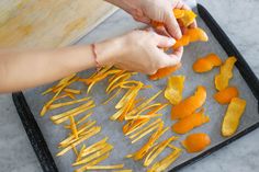 someone is peeling orange peels on a baking sheet in preparation to make an appetizer