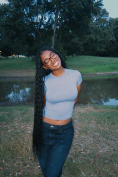 a woman standing in the grass with her long hair pulled back and smiling at the camera