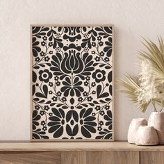 a black and white wall hanging next to two vases on a wooden table with flowers