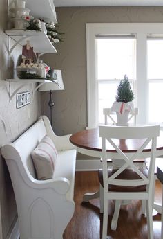 a table and chairs in a room with wooden floors, white walls and open windows