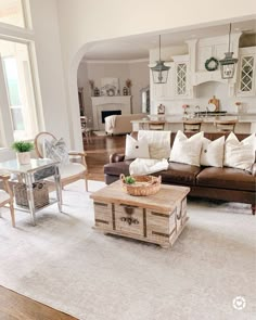 a living room filled with furniture next to a kitchen and dining room table on top of a white rug