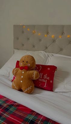 a teddy bear sitting on top of a bed next to a red pillow and blanket