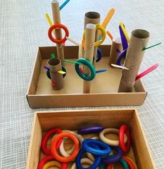 two cardboard boxes filled with different colored plastic rings and pencils on top of a table