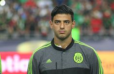 a soccer player is standing in front of the crowd with his head turned to look at the camera