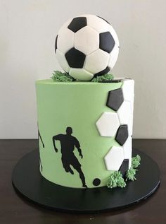 a soccer themed birthday cake with a ball on top and the silhouette of a man kicking a soccer ball