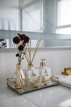 a bathroom counter with soap dispensers and flowers