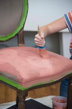 a person is painting a chair with pink paint and a green trim around the edge