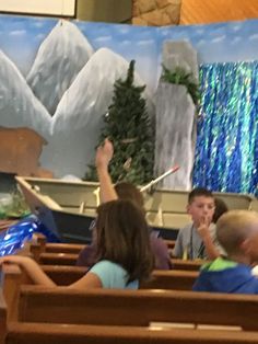 children are sitting in pews and raising their hands to sing at the same time