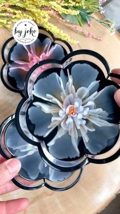 a person holding a flower in front of a wooden table with flowers on the side