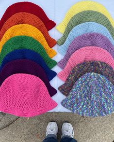 a person standing in front of a pile of crocheted hats with their feet on the ground