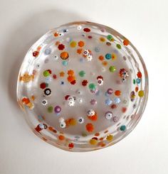 a glass plate with multicolored beads on the rim and bottom, sitting on a white surface