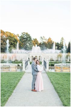 an engaged couple standing in front of a fountain