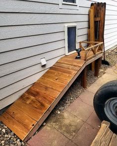 a dog door is open on the side of a house next to a wooden ramp