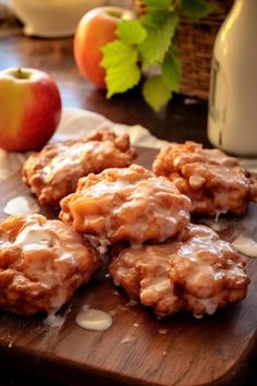 some cookies are on a cutting board with apples in the background