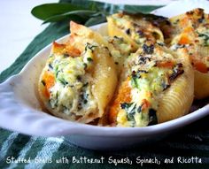 a white bowl filled with pasta and spinach on top of a green table cloth