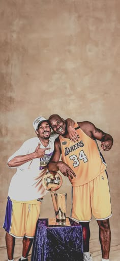 two men standing next to each other in front of a wall with a basketball trophy