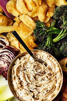 a bowl of dip surrounded by vegetables and crackers